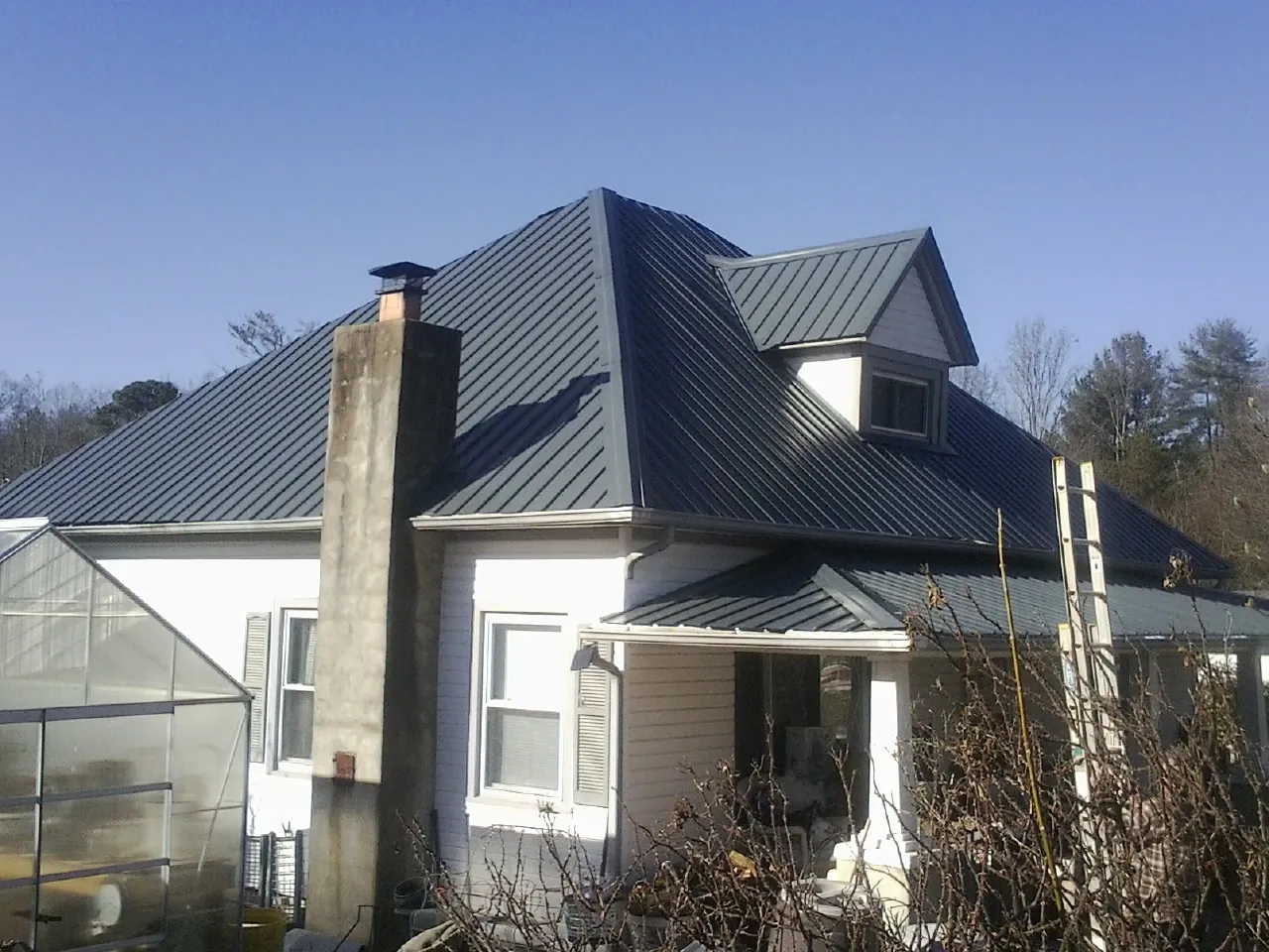 Dark blue standing seam metal roof on a white farmhouse with dormer — Slate & Tile Roof Repair by Roofing Brothers in Salinas