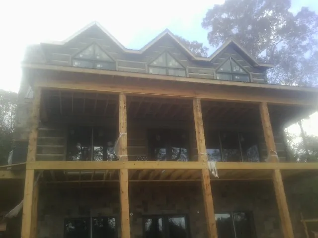 Dormers and porch framing on a large log home under construction — Roof Coating work by our crew in Salinas