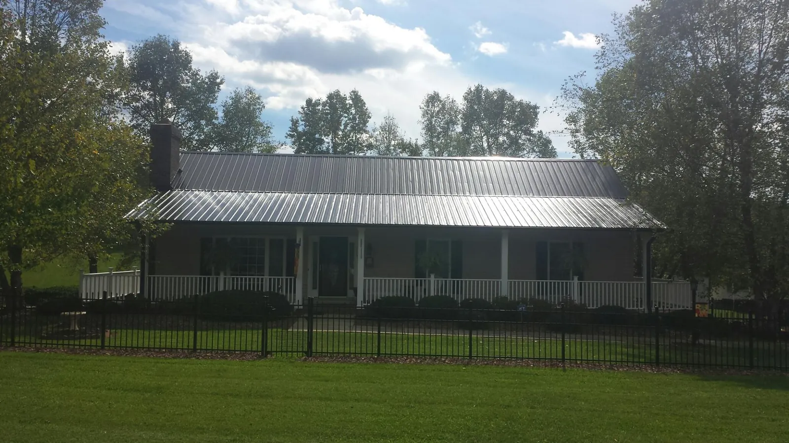 Gray metal roof on a brick ranch with a full width front porch — Gutter Guard Installation work by our crew in Salinas