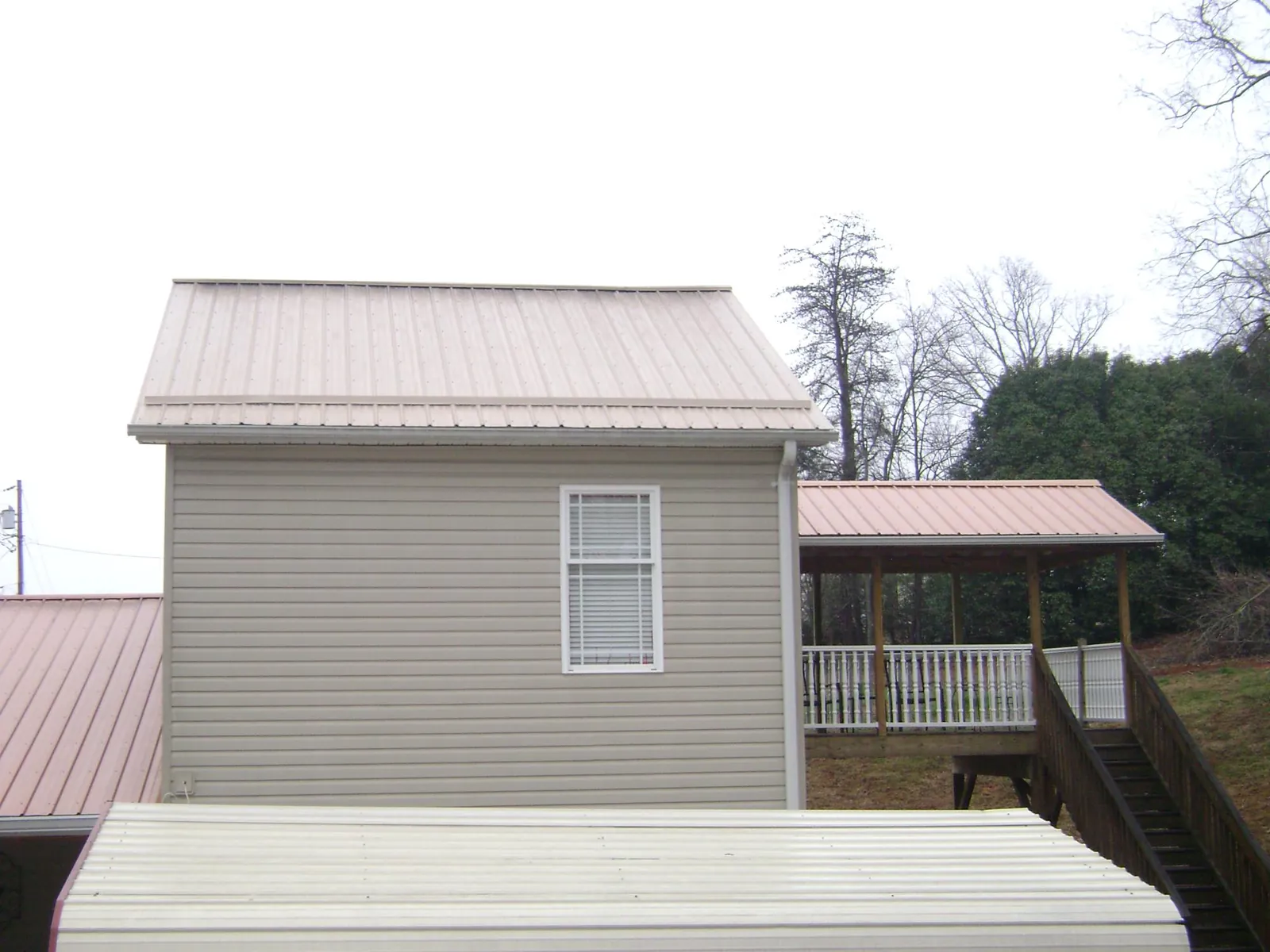Tan metal roofs on a two story addition and attached porch, from a Roof Replacement job in Salinas