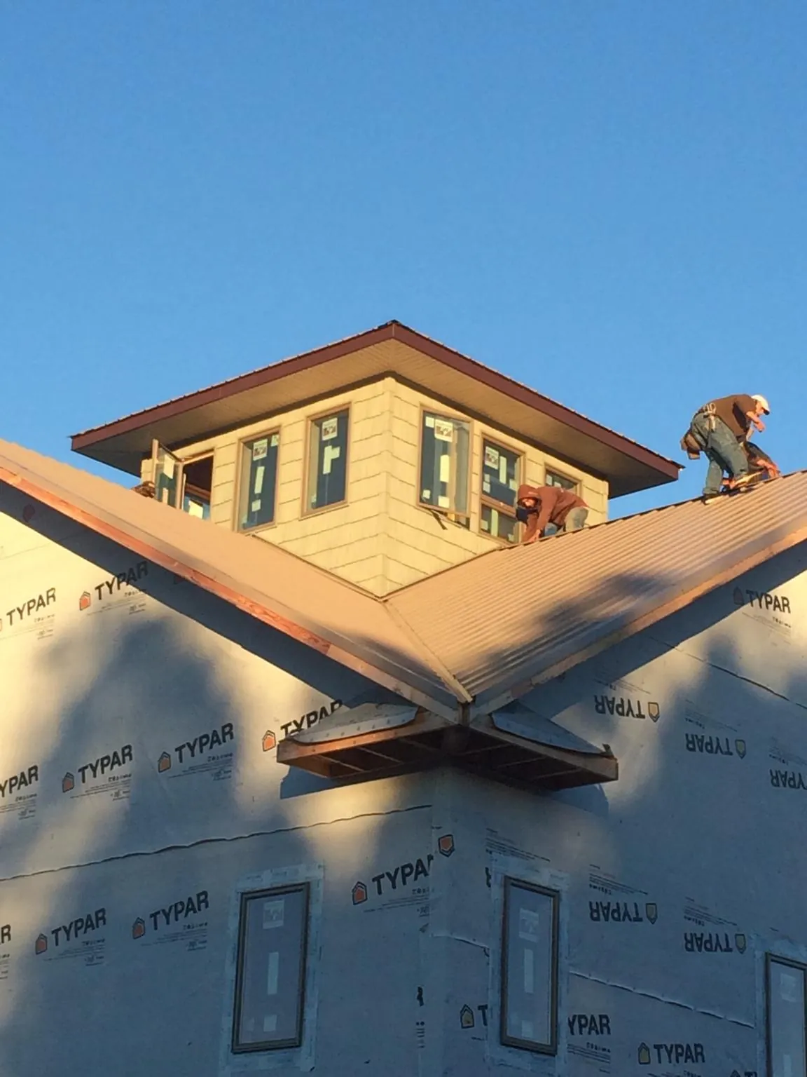Roofers working around a rooftop cupola on a new metal roof at sunset — Roof Waterproofing in Salinas by Roofing Brothers